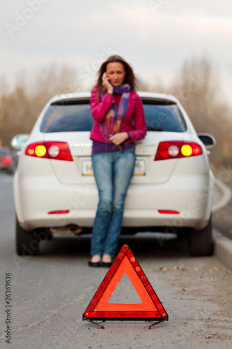Woman calls to a service standing by a white car. © Nobilior
