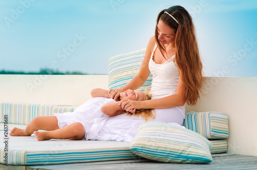 Young mother and her daughter relax in sea background