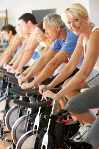 Senior Woman Cycling In Spinning Class In Gym