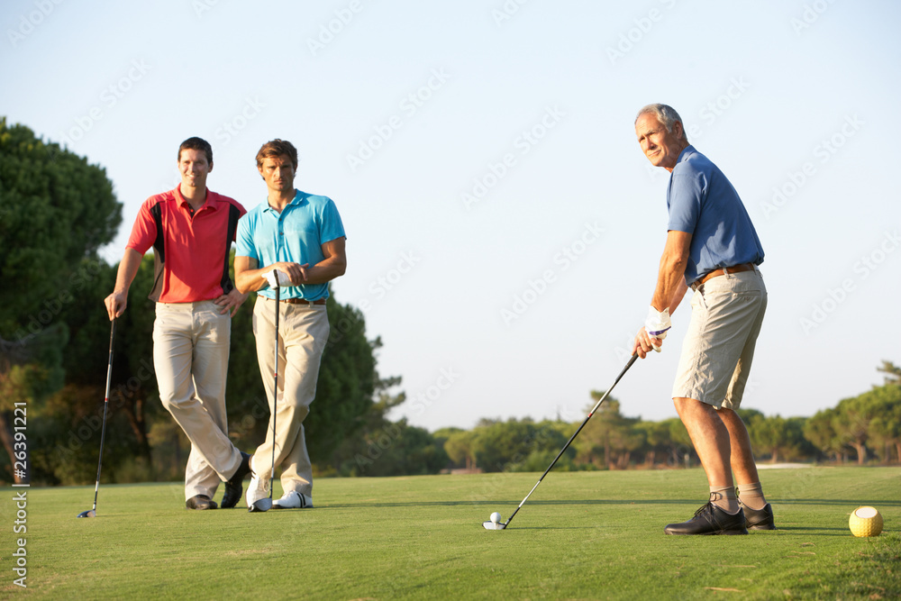 Obraz premium Group Of Male Golfers Teeing Off On Golf Course