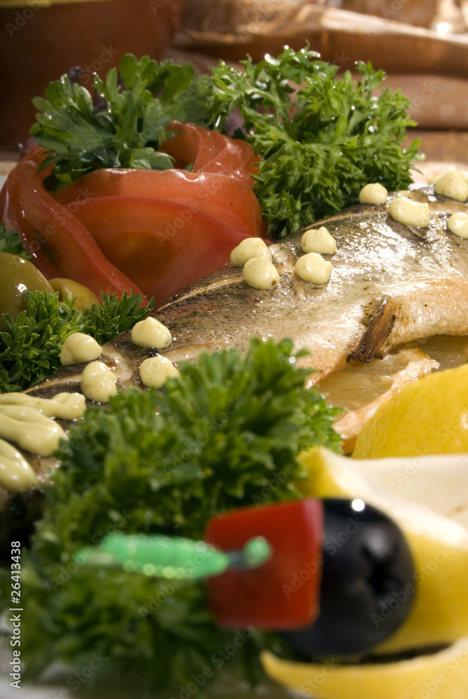 Stuffed baked fish served with lemon and salad Stuffed baked fish served with lemon and salad