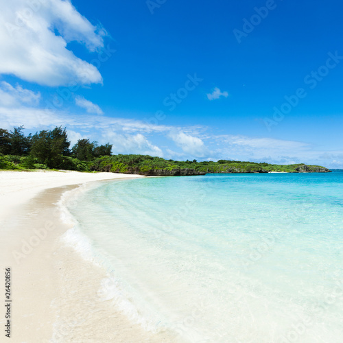 Deserted tropical beach on coral island with clear blue water