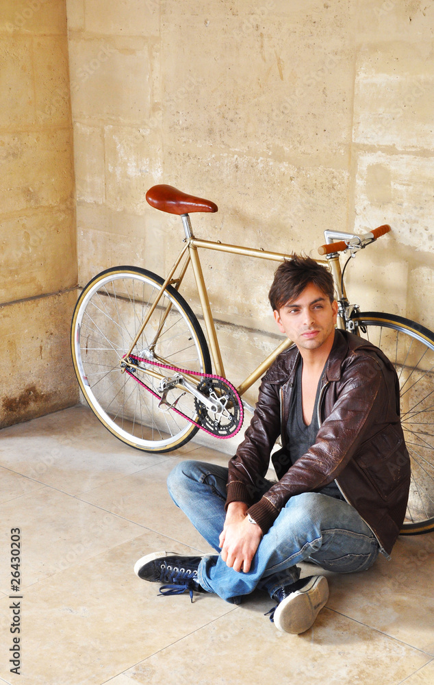 Young man sitting in front of his fixed-gear bicycle Young man sitting in front of his fixed-gear bicycle