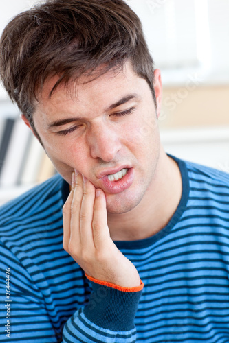 portrait of a man having a raging toothache sitting in the livin photo