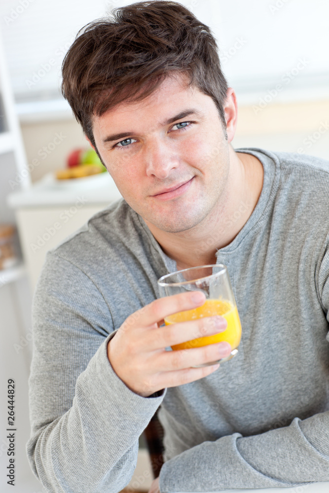 Attractive young man drinking orange juice in the kitchen Attractive young man drinking orange juice in the kitchen