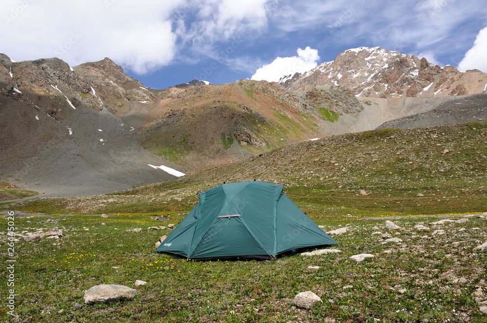 Tent in mountains with sky and clouds