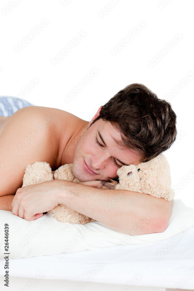 young man in pyjamas sleeping with a teddy-bear lying on his bed young man in pyjamas sleeping with a teddy-bear lying on his bed
