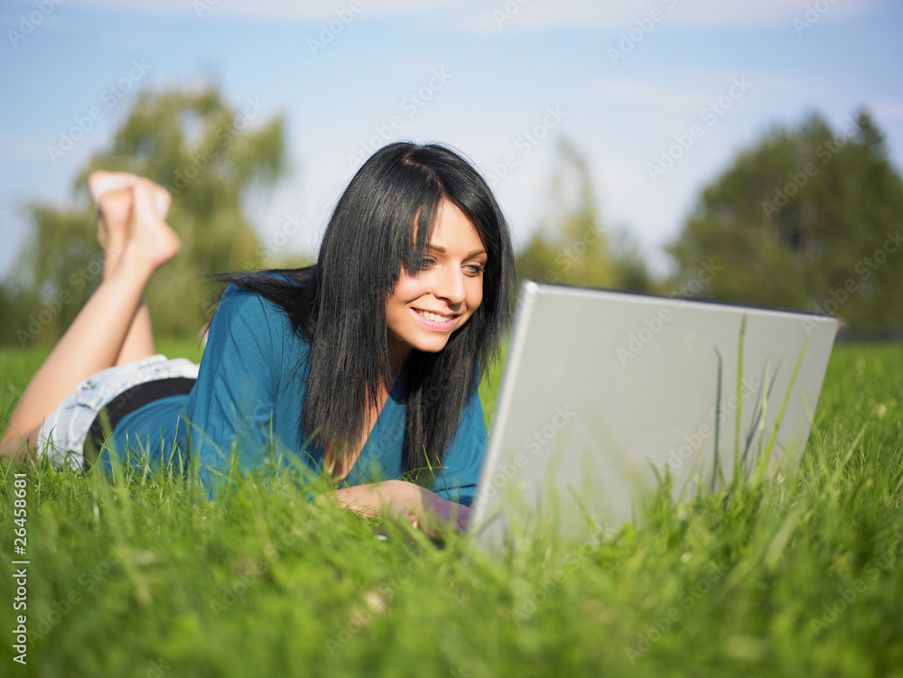 Young woman using laptop in park Young woman using laptop in park