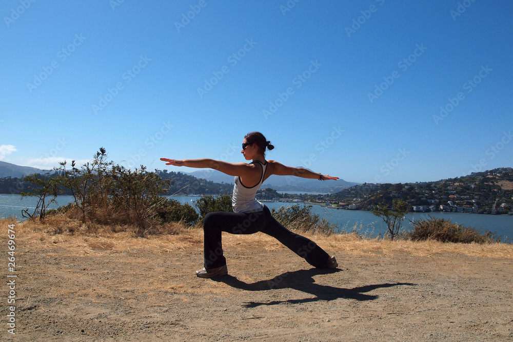 Attractive 20-something lady does Warrior Two Yoga Pose Attractive 20-something lady does Warrior Two Yoga Pose