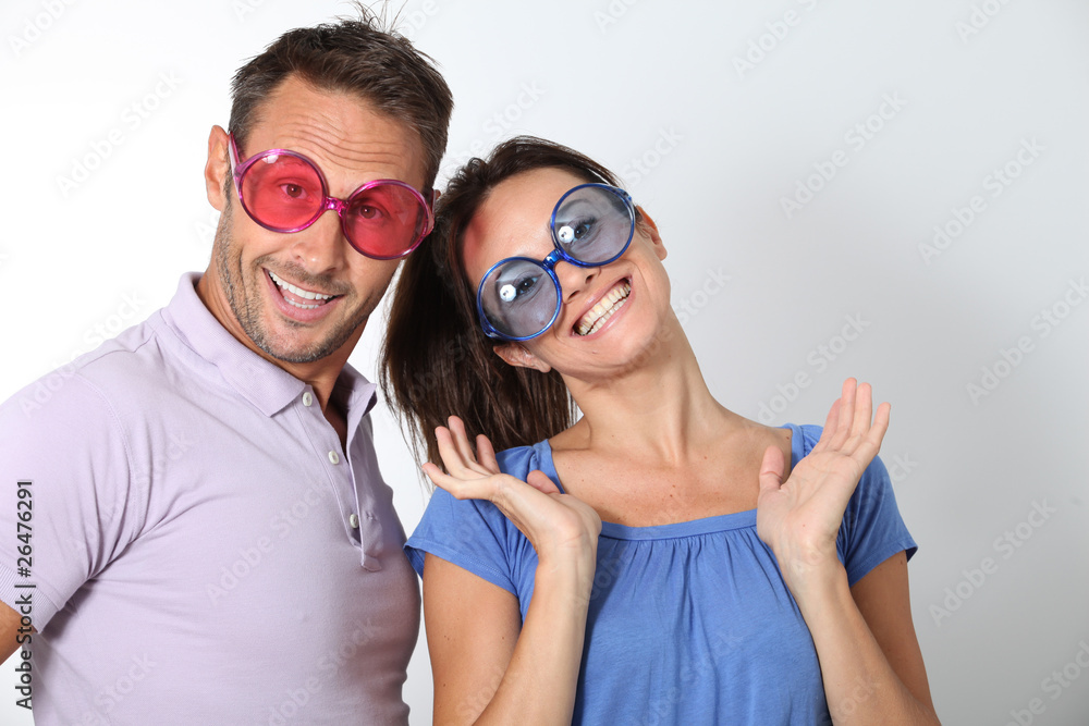 Couple wearing colored glasses having fun on white background