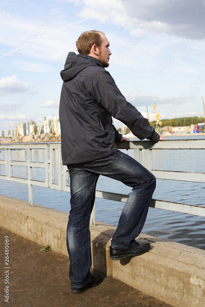 young man standing on river embankment and looking into the dist young man standing on river embankment and looking into the dist