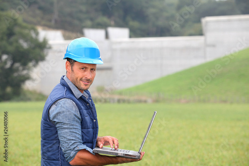 Engineer standing in front of dam under construction