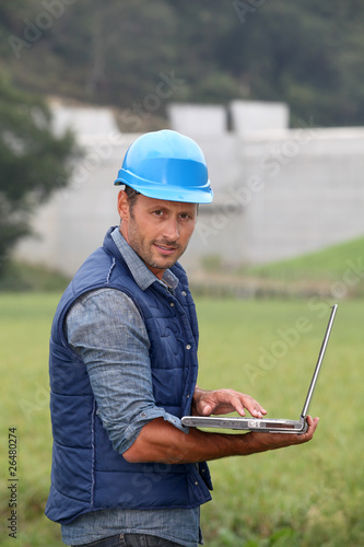 Engineer standing in front of dam under construction