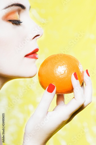 Woman portrait smelling an orange tangerine fruit