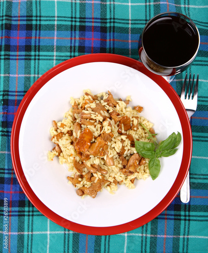 Risotto with mushrooms and glass of red wine on table cloth photo