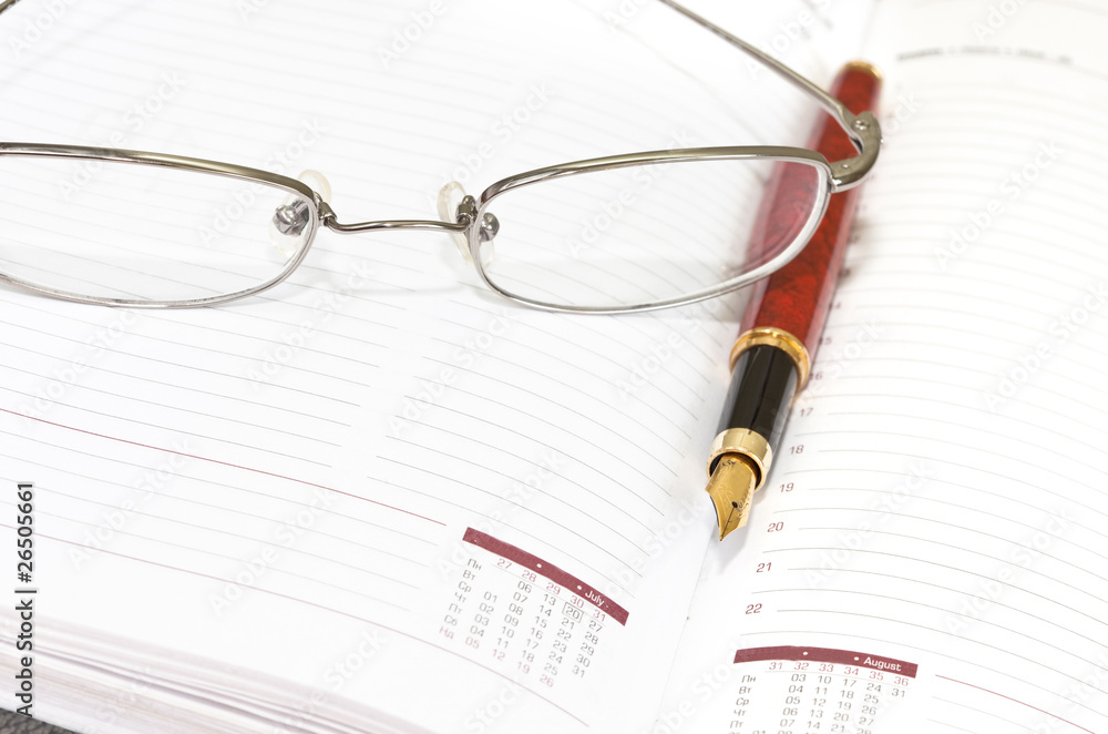 Daily planner with glasses and pen Daily planner with glasses and pen