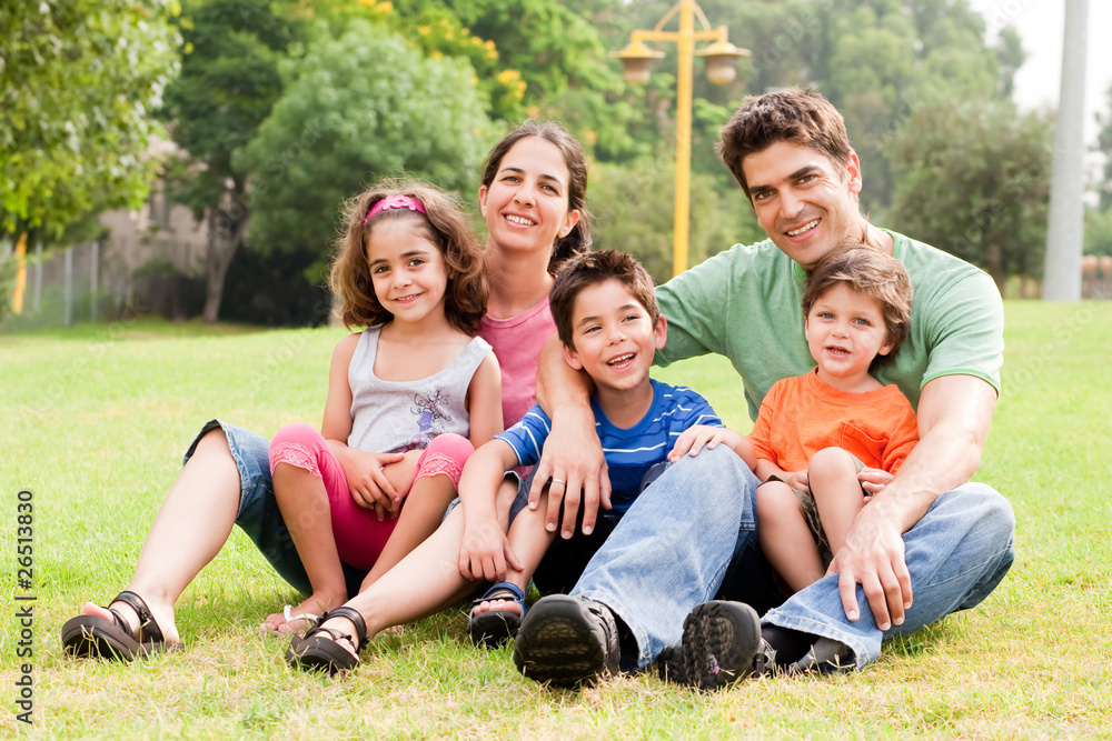 Family seated in park and smiling at camera Family seated in park and smiling at camera