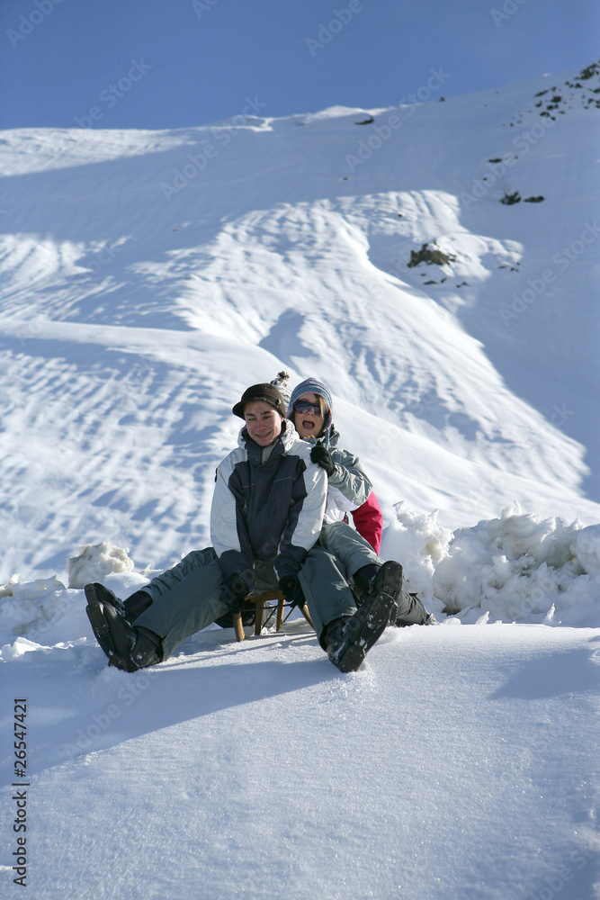 Groupe d'amis assis sur une luge à la neige