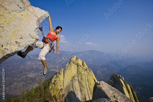 Female rock climber rappelling.