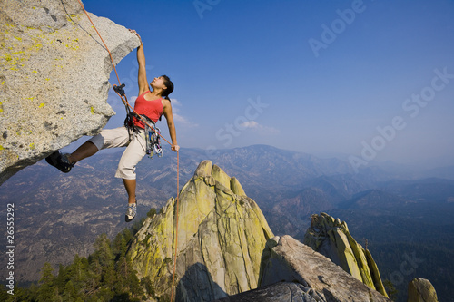 Female rock climber rappelling.