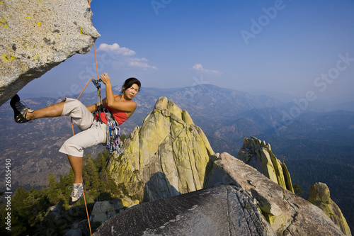 Female rock climber rappelling.