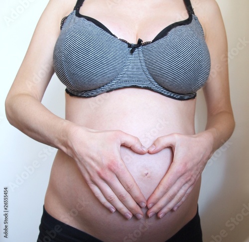 Pregnant woman with hands on her belly forming a heart