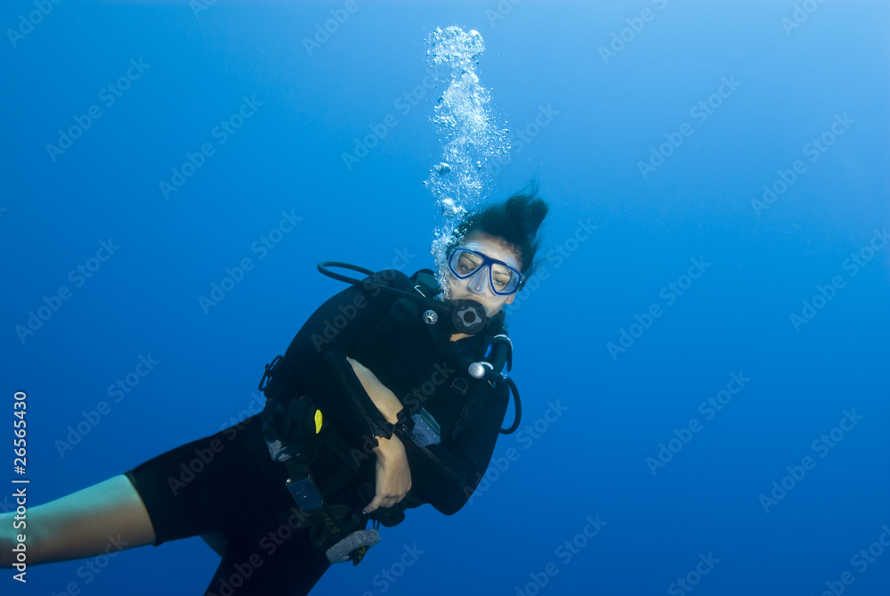 Adult female scuba diver in blue water.