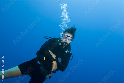 Adult female scuba diver in blue water.