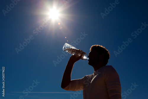 Mann trinkt Wasser aus Flasche unter Sonne
