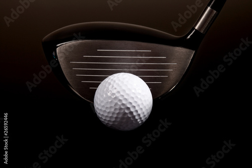 a close-up of a golf driver and golf ball on black