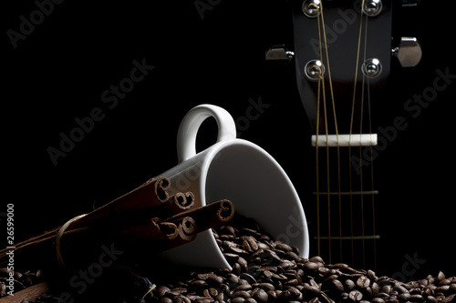 coffee mug beans cinnamon sticks and guitar on black