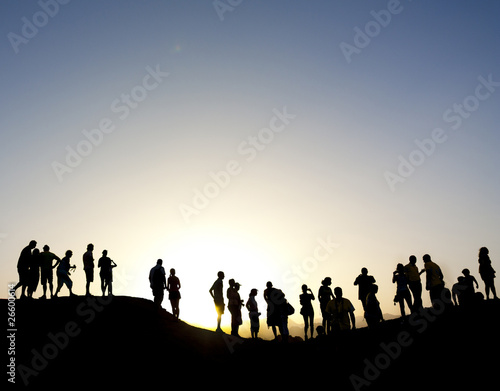 Group of people silhouetted against the sun on top of a mountain