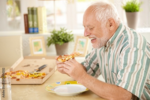 Smiling older man eating pizza slice
