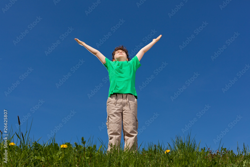 Hope - boy holding arms up against blue sky Hope - boy holding arms up against blue sky