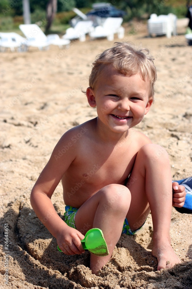 Laughing child with shovel on a sand beach Laughing child with shovel on a sand beach