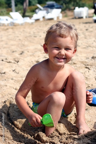 Laughing child with shovel on a sand beach
