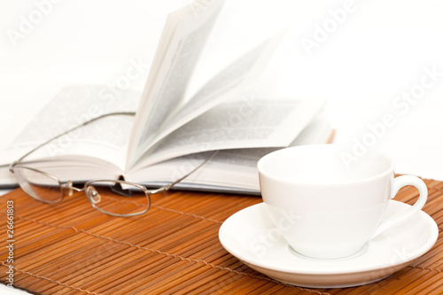 white cup of coffee and book with glasses