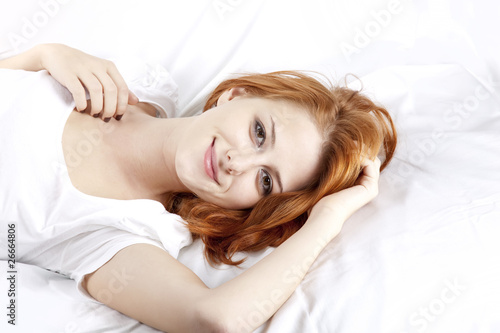 Pretty red-haired sleeping woman in white nightie lying in the b