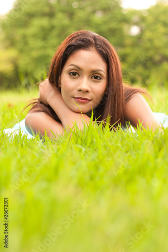 Romantic portrait of young lady lying on grass