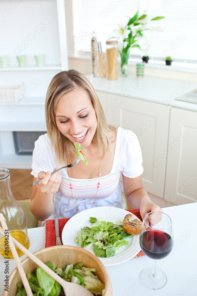 Portrait of a beautiful woman eating a salad in the kitchen