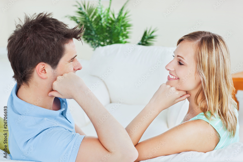 Young couple playing to look at each other sitting on the sofa Young couple playing to look at each other sitting on the sofa