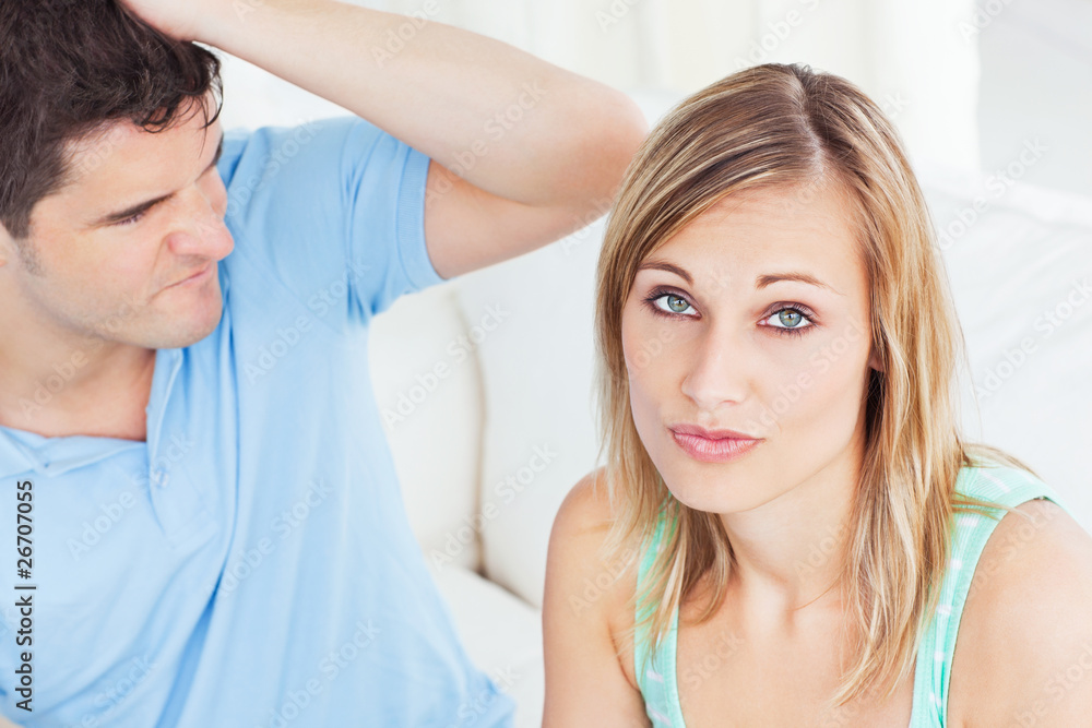 Young woman ignoring her boyfriend sitting on the sofa at home Young woman ignoring her boyfriend sitting on the sofa at home