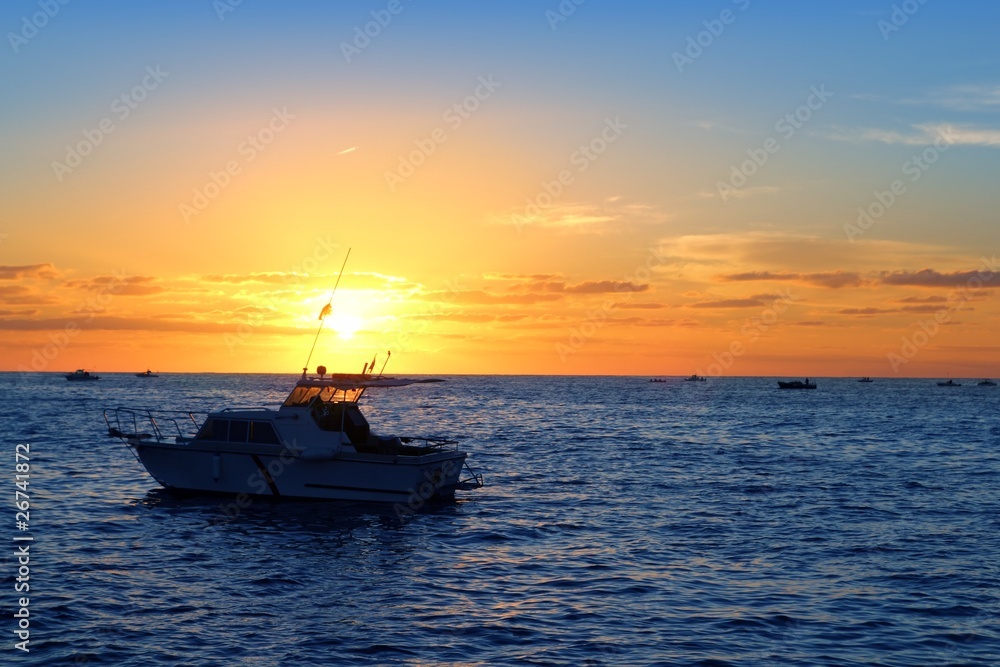 Naklejka premium Sunrise fishing boat blue sea orange sky