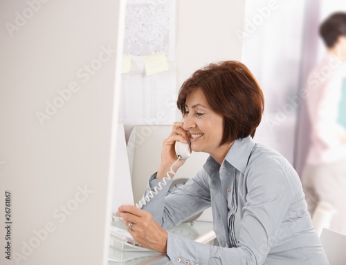 Mature businesswoman talking on landline phone