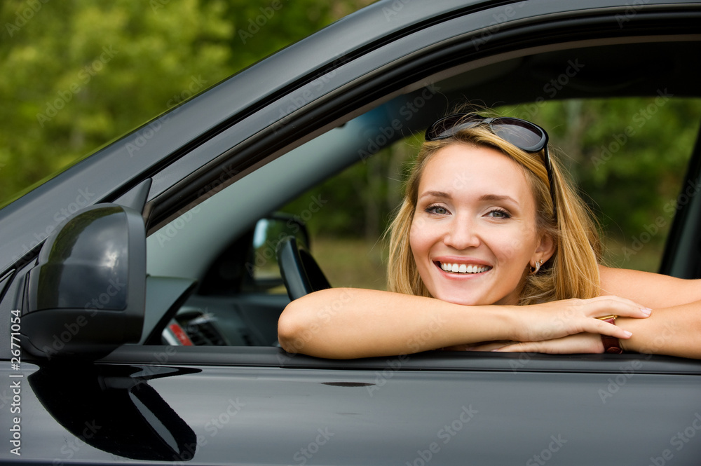 happy beautiful young woman posing in the new car