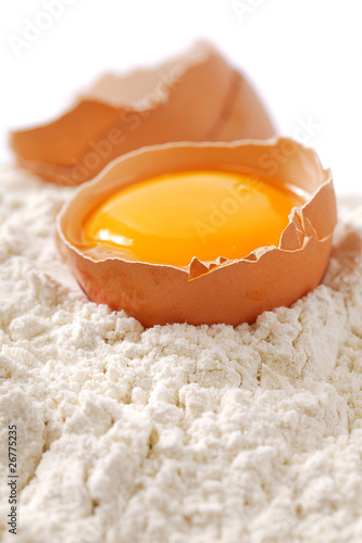 Broken egg with shells on flour  white backdrop