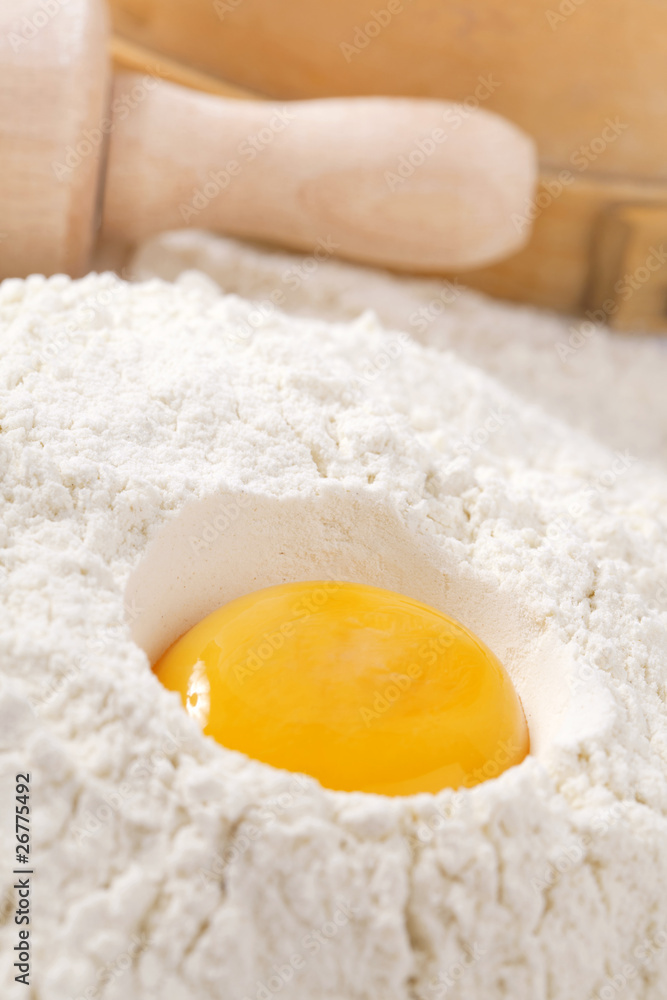 egg yolk in flour, rolling pin ang sieve on background egg yolk in flour, rolling pin ang sieve on background