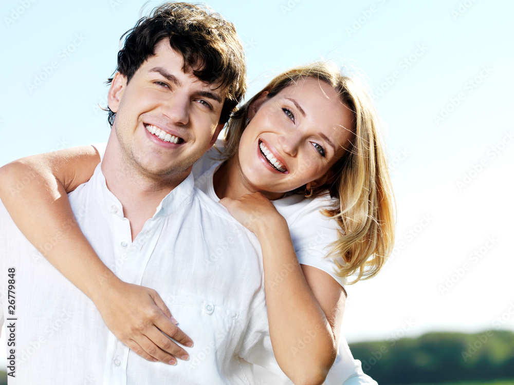 beautiful young smiling couple on blue sky background beautiful young smiling couple on blue sky background