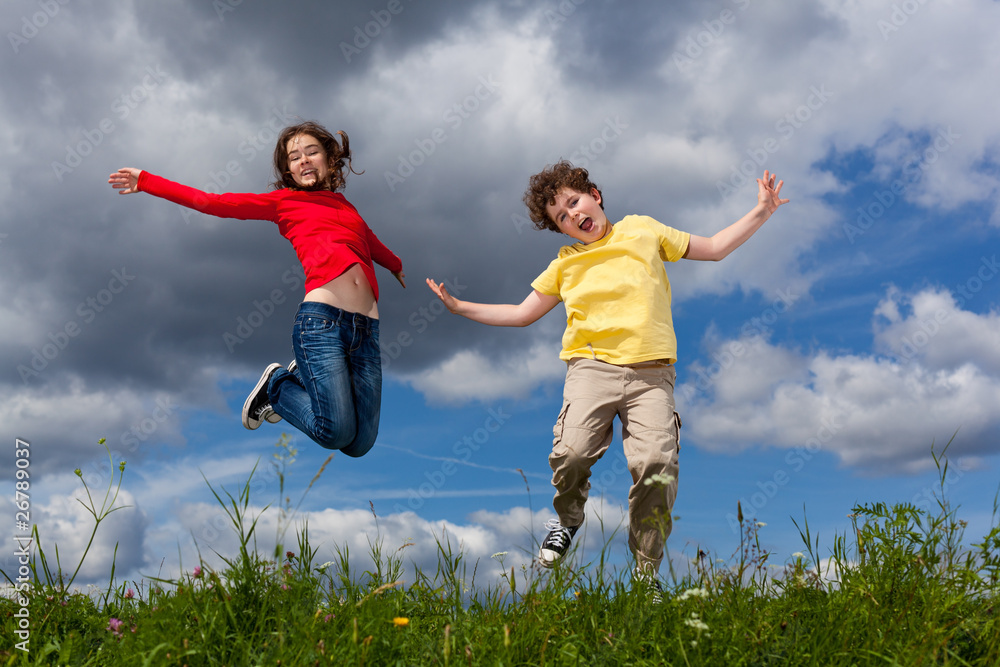 Girl and boy jumping, running against blue sky Girl and boy jumping, running against blue sky
