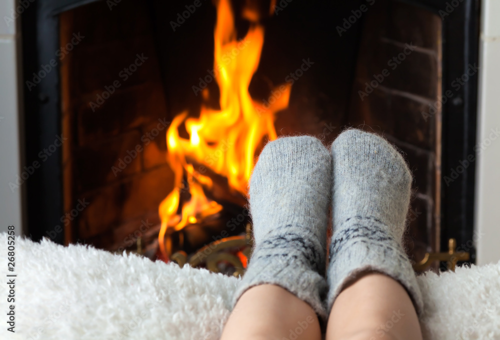 Children's feet are heated in the fireplace - obrazy, fototapety, plakaty 